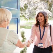 Senior woman greeting female care worker making home visit