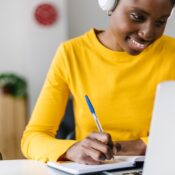 Smiling african woman student using laptop computer for online learning at home